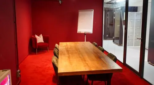 Vergaderruimte met houten tafel en stoelen in kantoorpand op Weesperplein 4b, Amsterdam Centrum. De ruimte heeft rode muren en vloerbedekking en is ideaal voor kantoorruimte huren.