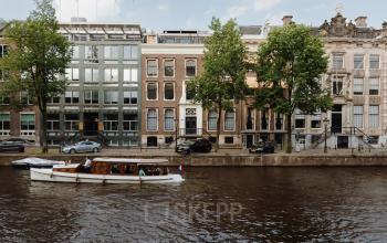 Buitenaanzicht van een kantoorpand aan de Herengracht 471 in Amsterdam Centrum, gelegen aan de gracht met voorbijvarende boot.