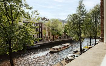 Buitenzicht op de Herengracht 471 in Amsterdam Centrum met historische panden en een passerende rondvaartboot.