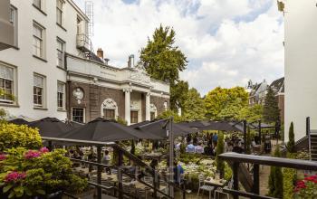 Buitenterrein van kantoorpand Herengracht 471 in Amsterdam Centrum met terras en mensen die zakelijke gesprekken voeren.