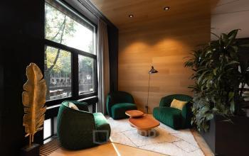 Knusse kantoorruimte aan de Herengracht 471 in Amsterdam Centrum met groene fauteuils, houten wanden en veel natuurlijk licht.
