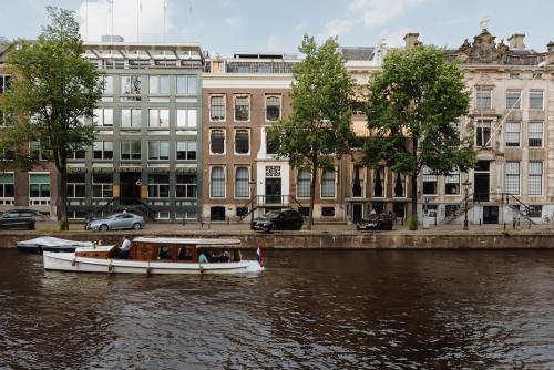 Buitenaanzicht van een kantoorpand aan de Herengracht 471 in Amsterdam Centrum, gelegen aan de gracht met voorbijvarende boot.
