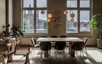 Vergaderruimte in kantoorpand met ramen en uitzicht op Amsterdamse architectuur, gelegen op Stationsplein 9, Amsterdam Centrum.
