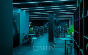 Modern kantoor gelegen op Stationsplein 9, Amsterdam Centrum, met een strak industrieel interieur en werkplekken met fitnessapparatuur.