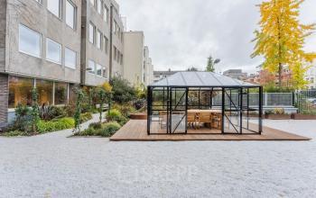 Gevel van het kantoorpand op Weesperstraat 107-121, Amsterdam Centrum, met een moderne glazen serre in de tuin, omgeven door groenvoorzieningen.