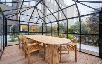 Moderne glazen ruimte aan de Weesperstraat 107-121 in Amsterdam Centrum, ingericht met een houten tafel en stoelen, ideaal voor kantoorgebruik. Geschikt voor kantoorruimte huren in een inspirerende omgeving.