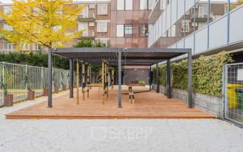 Exterieur van kantoorpand aan de Weesperstraat 107-121 in Amsterdam Centrum, met moderne pergola en houten terras, geschikt voor diverse activiteiten.