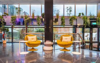 Modern interieur met kleurrijke stoelen en planten in een lichte kantoorlobby aan de Weesperstraat 107-121, Amsterdam Centrum, ideaal voor kantoorruimte huren.