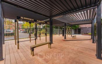 Open houten buitenruimte op Weesperstraat 107-121, Amsterdam Centrum, met moderne pergola. Ideaal voor ontspannen na een dag in het kantoorpand. Geen personen te zien.