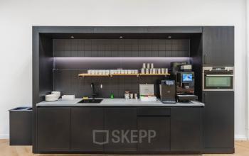 Moderne pantry in het kantoorpand aan de Weesperstraat 107-121 in Amsterdam Centrum, uitgerust met een koffieapparaat en servies, ideaal voor huurders die een functionele kantoorruimte zoeken.