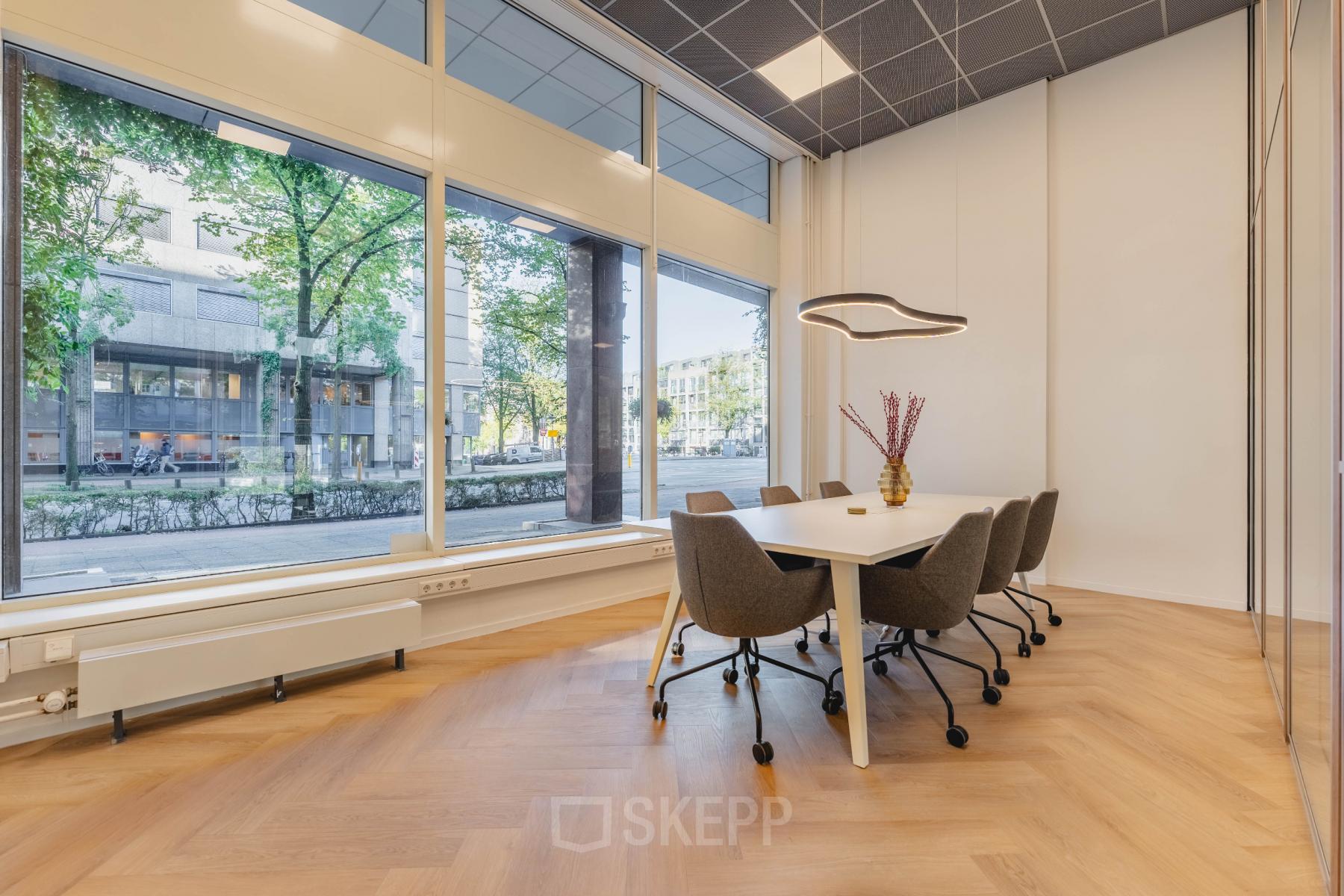 Vergaderruimte met lange tafel en stoelen, grote ramen met uitzicht Weesperstraat, Amsterdam Centrum. ideaal voor kantoorruimte huren.