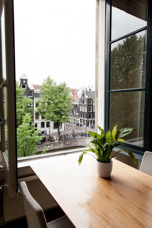 Kantoor aan Keizersgracht 241 in Amsterdam Centrum met uitzicht op de gracht, houten tafel, plantenbak, en open raam.