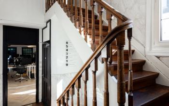 Kantoorpand op Rokin 46-1 in Amsterdam Centrum, met een stijlvolle houten trap en uitzicht naar een moderne kantoorruimte voor huur.