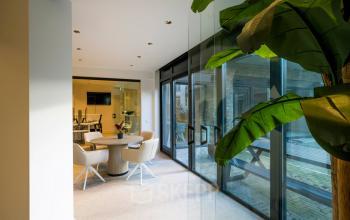 Moderne kantoorruimte huren bij Groenmarktkade 5-H in Amsterdam Centrum met stijlvolle glazen wand en elegant meubilair, ideaal voor zakelijke vergaderingen en samenwerken in een inspirerende omgeving.