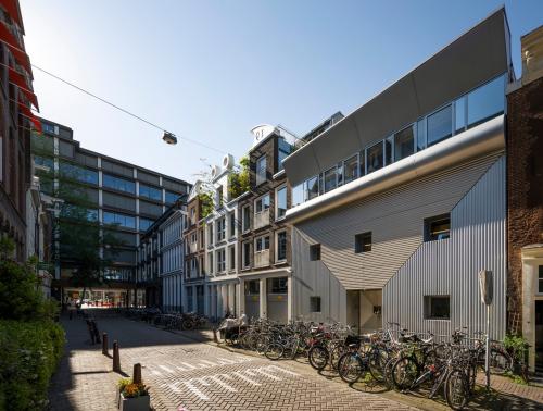 Kantoorpand in Amsterdam Centrum op Kerkstraat 204, omringd door fietsen. Moderne architectuur en een lichtblauwe lucht benadrukken de stedelijke sfeer. Ideale locatie om kantoorruimte te huren.