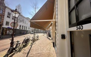 Entree van het kantoorpand gelegen aan Nieuwezijds Voorburgwal 340, Amsterdam Centrum, met uitzicht op de straat en fietsen. Ideaal voor kantoorruimte huren in het hart van de stad.