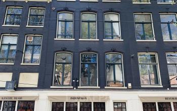 Kantoorpand aan de Nieuwezijds Voorburgwal 340 in Amsterdam Centrum. Historisch pand met donkere gevel en grote ramen. Ideaal om kantoorruimte te huren in een karakteristieke omgeving.