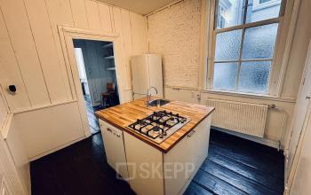 Keuken op Nieuwezijds Voorburgwal 340 in Amsterdam Centrum met houten werkblad, gaskookplaat en koelkast. Ideaal voor kantoorruimte huren met compacte pantry faciliteit.