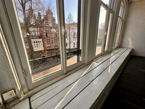 Uitzicht vanaf een grote vensterbank in een kantoorpand aan de Nieuwezijds Voorburgwal 340, Amsterdam Centrum. De kamer is ongemeubileerd en rustig, ideaal om kantoorruimte te huren met karakteristieke ramen.