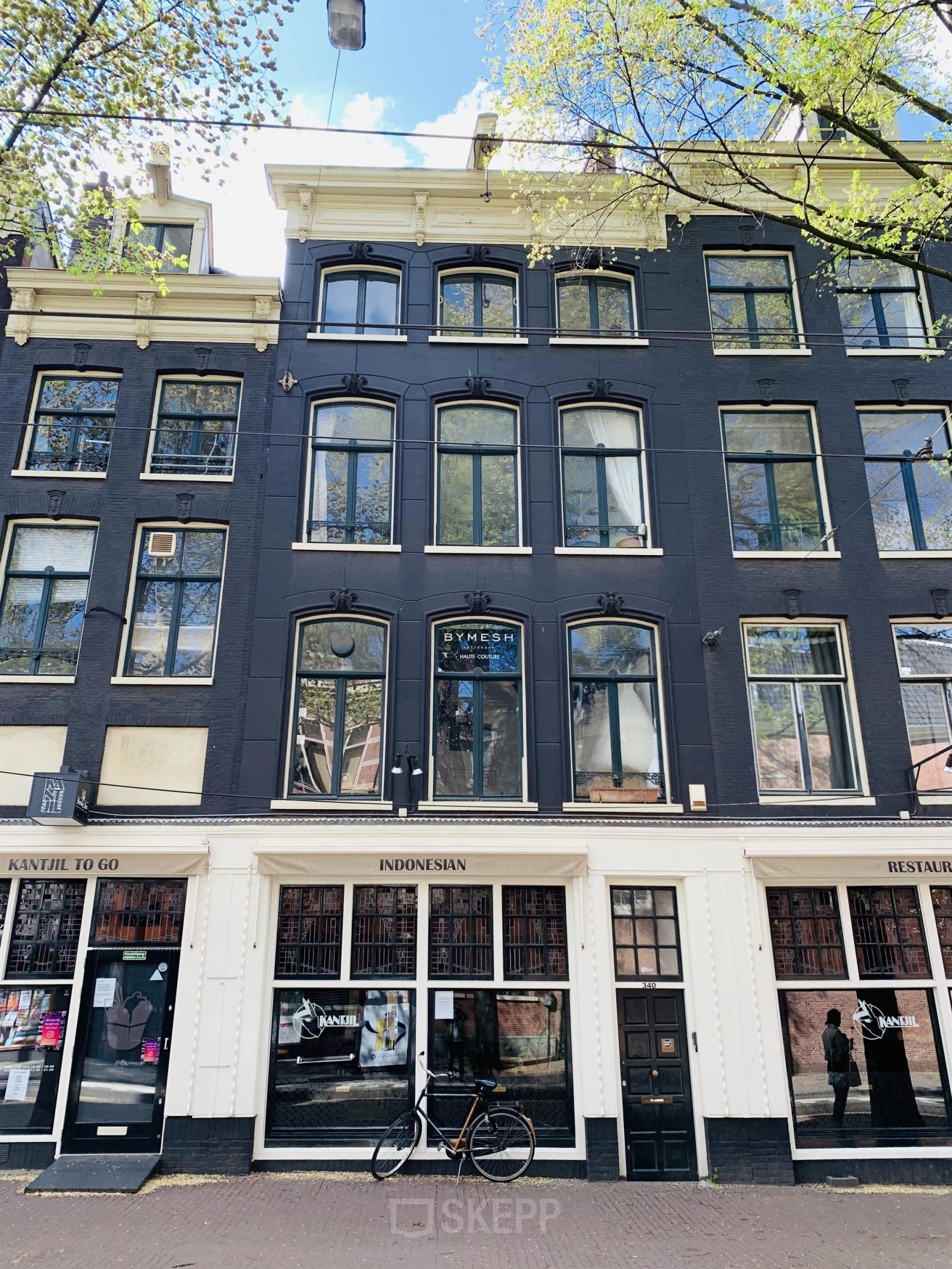 Kantoorpand aan de Nieuwezijds Voorburgwal 340 in Amsterdam Centrum. Historisch pand met donkere gevel en grote ramen. Ideaal om kantoorruimte te huren in een karakteristieke omgeving.