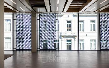 Lichte kantoorruimte te huur op Pieter Cornelisz. Hooftstraat 7 in Amsterdam Centrum, met grote ramen en uitzicht op een klassiek pand. De ruimte is ongemeubileerd en toont een modern interieur.