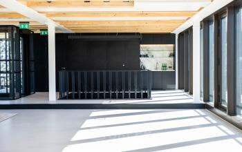 Lichte, moderne kantoorruimte met houten plafondbalken en een trap naar beneden. Ruimte voor huren als kantoor op Pieter Cornelisz. Hooftstraat 7, Amsterdam Centrum.