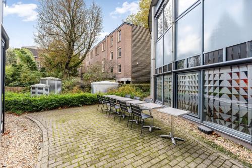 Buitenruimte van kantoorpand op Stadhouderskade 55 in Amsterdam Centrum met tafels en stoelen, omringd door groene beplanting en naastliggende gebouwen.