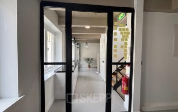 Modern kantoor met glazen deur en strakke afwerking op Kloveniersburgwal 131K, Amsterdam Centrum. Ideaal voor kantoorruimte huren met ruime werkplek en veel natuurlijk licht.