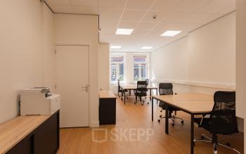Lichte kantoorruimte te huur aan de Korte Leidsedwarsstraat 133A, Amsterdam Centrum, met houten vloeren, bureaus en stoelen.