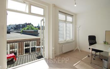 Kantoorruimte huren op Warmoesstraat 149-151 in Amsterdam Centrum met balkon en uitzicht op de stad, ingericht met bureau en stoel.