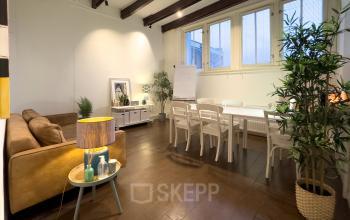 Interieur van een kantoorpand aan de Warmoesstraat 149-151 in Amsterdam Centrum. Moderne werkruimte met houten vloeren, lange tafel en gezellige zithoek. Ideaal voor kantoorruimte huren.