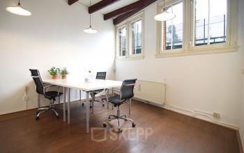 Modern ingerichte kantoorruimte in het kantoorpand aan Warmoesstraat 149 - 151 in Amsterdam Centrum, met bureau en stoelen.