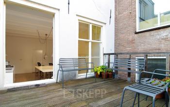 Terras van kantoorpand op Warmoesstraat 155 in Amsterdam Centrum met zicht op een vergaderruimte. Perfecte plek voor een brainstormsessie of korte pauze. Beneden kantoorruimte huren in hartje Amsterdam.