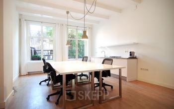 Lichte kantoorruimte huren op Warmoesstraat 155, Amsterdam Centrum, met ruime tafels en een keukenhoek voor een efficiënte werkomgeving.