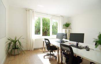 Lichte kantoorruimte huren aan de Warmoesstraat 155, Amsterdam Centrum, met grote ramen en moderne bureaus, perfect voor een inspirerende werkomgeving.