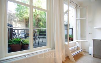 Kantoorruimte huren in Amsterdam Centrum op Warmoesstraat 155 met uitzicht op een terras, voorzien van grote ramen en lichte houten vloeren.