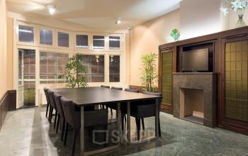Vergaderruimte in kantoorpand op Warmoesstraat 155 in Amsterdam Centrum met grote tafel en comfortabele stoelen, planten en glazen kast. Ideaal voor kantoorruimte huren.