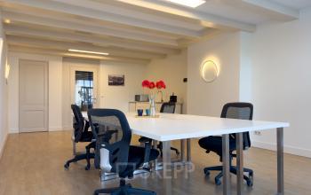 Lichte kantoorruimte met houten vloer op Warmoesstraat 155, Amsterdam Centrum. Moderne stoelen en tafel in open opstelling geschikt voor huur als werkplek.