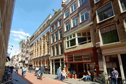 Buitenaanzicht van het kantoorpand op Warmoesstraat 155, Amsterdam Centrum, met mensen die wandelen en fietsen langs het pand.