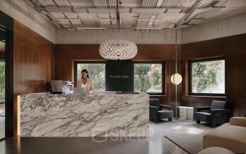 Moderne receptieruimte in kantoorpand op Weteringschans 126, Amsterdam Centrum, met design interieur en marmeren balie. Persoon bezig achter laptop bij de receptie.