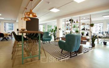 Gezellig open kantoor op Kleine Gartmanplantsoen 21, Amsterdam met comfortabele zitplekken en groene accenten. Ideale kantoorruimte huren voor creatieve professionals.