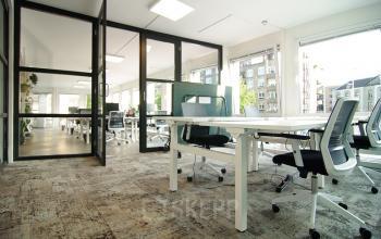 Moderne kantoorruimte Kleine Gartmanplantsoen 21 Amsterdam Centrum met glazen scheidingswanden, witte bureaus en ergonomische stoelen.