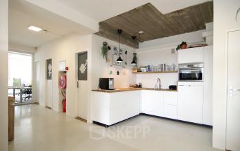 Moderne kantoorpand pantry met witte kasten en apparatuur aan het Kleine Gartmanplantsoen 21, in het levendige Amsterdam Centrum.