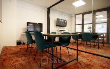 Moderne kantoorruimte met grote vergadertafel en comfortabele stoelen, gelegen op Kleine Gartmanplantsoen 21 in Amsterdam Centrum.