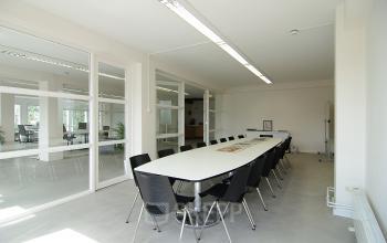 Moderne kantoorruimte met lange vergadertafel en stoelen, gelegen op Kleine Gartmanplantsoen 21 in Amsterdam Centrum, voorzien van natuurlijke lichtinval.