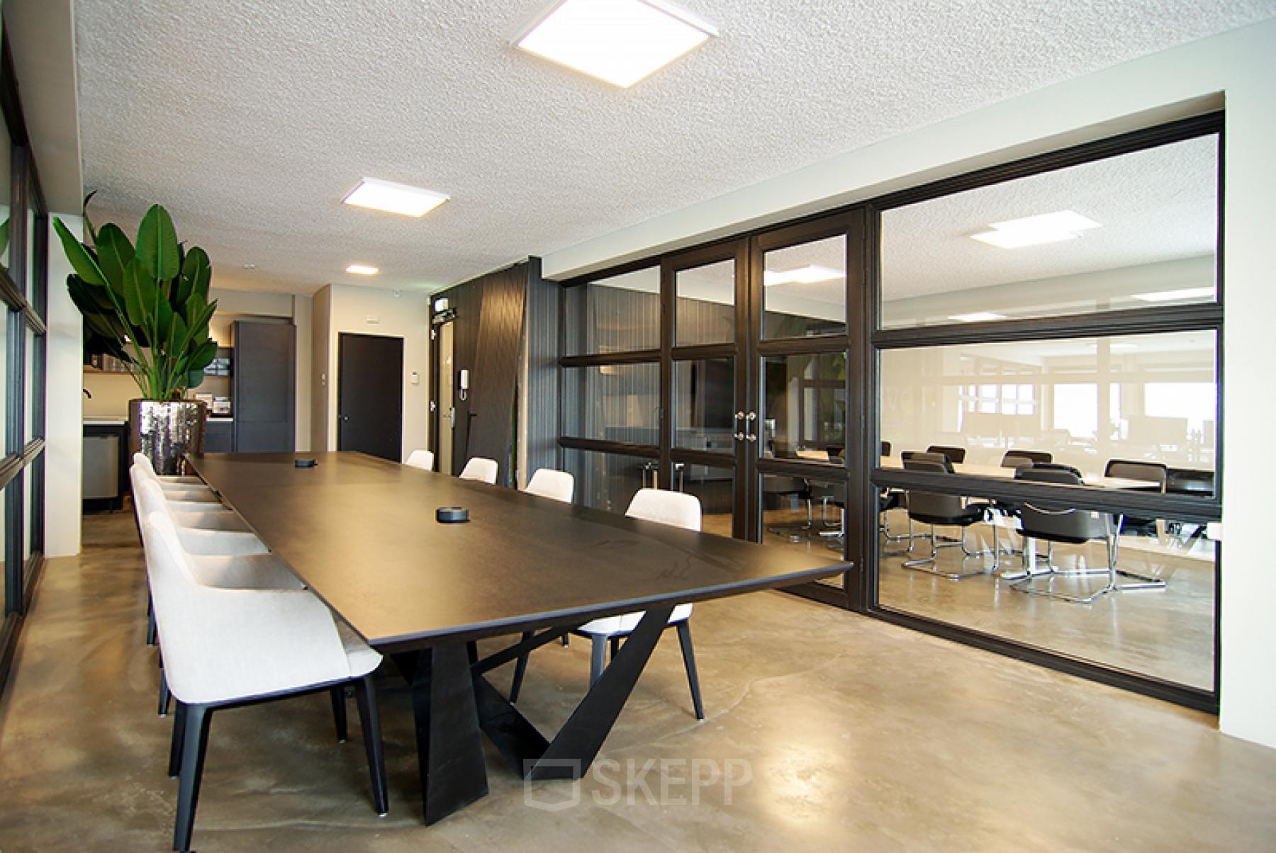 Moderne vergaderruimte in het kantoorpand op Kleine Gartmanplantsoen 21, Amsterdam Centrum, met grote tafel, stoelen en glazen wanden.