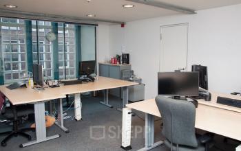 Kantoorpand aan het Zuiderkerkhof 72 in Amsterdam Centrum, ingericht met meerdere bureaus, stoelen, en computers voor werkruimte huren. Grote ramen zorgen voor natuurlijk licht.