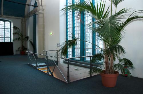 Binnenkant van een kantoorpand op Zuiderkerkhof 72, Amsterdam Centrum, met grote ramen, groene planten en een moderne trap. Ideaal voor wie kantoorruimte huren wil in een lichte omgeving.