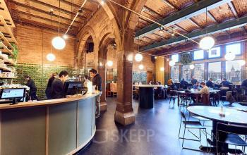 Modern ingerichte kantoorruimte met hoge plafonds en bakstenen muren aan Oudebrugsteeg 9, Amsterdam Centrum, ideaal om te huren voor zakelijke doeleinden.