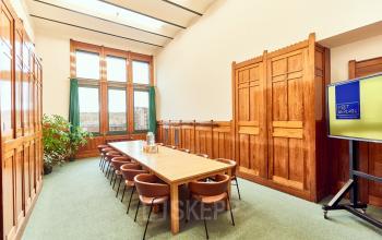 Een representatieve vergaderruimte binnen een kantoorpand op Oudebrugsteeg 9, in Amsterdam Centrum, met houten lambrisering en een grote tafel met stoelen.